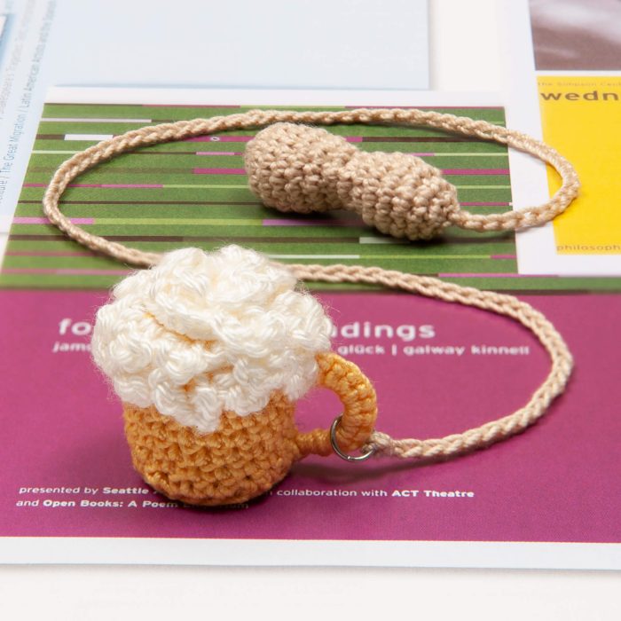 Crochet Handmade Beer Glass With Crochet Peanut Tassel On Book Angle Shot